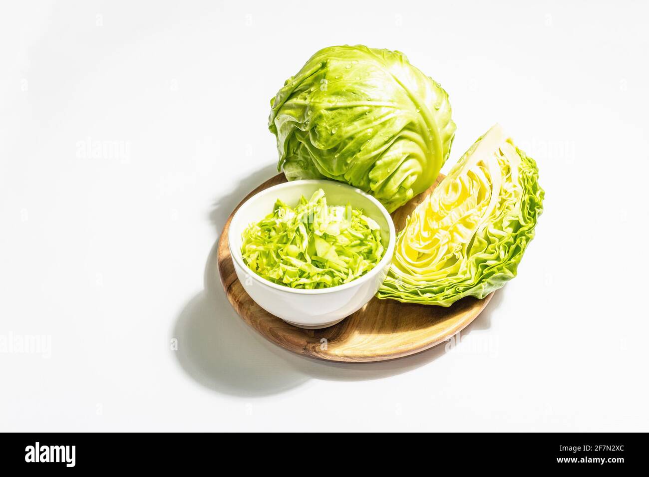 Fresh young shredded cabbage, whole head and cut piece isolated in