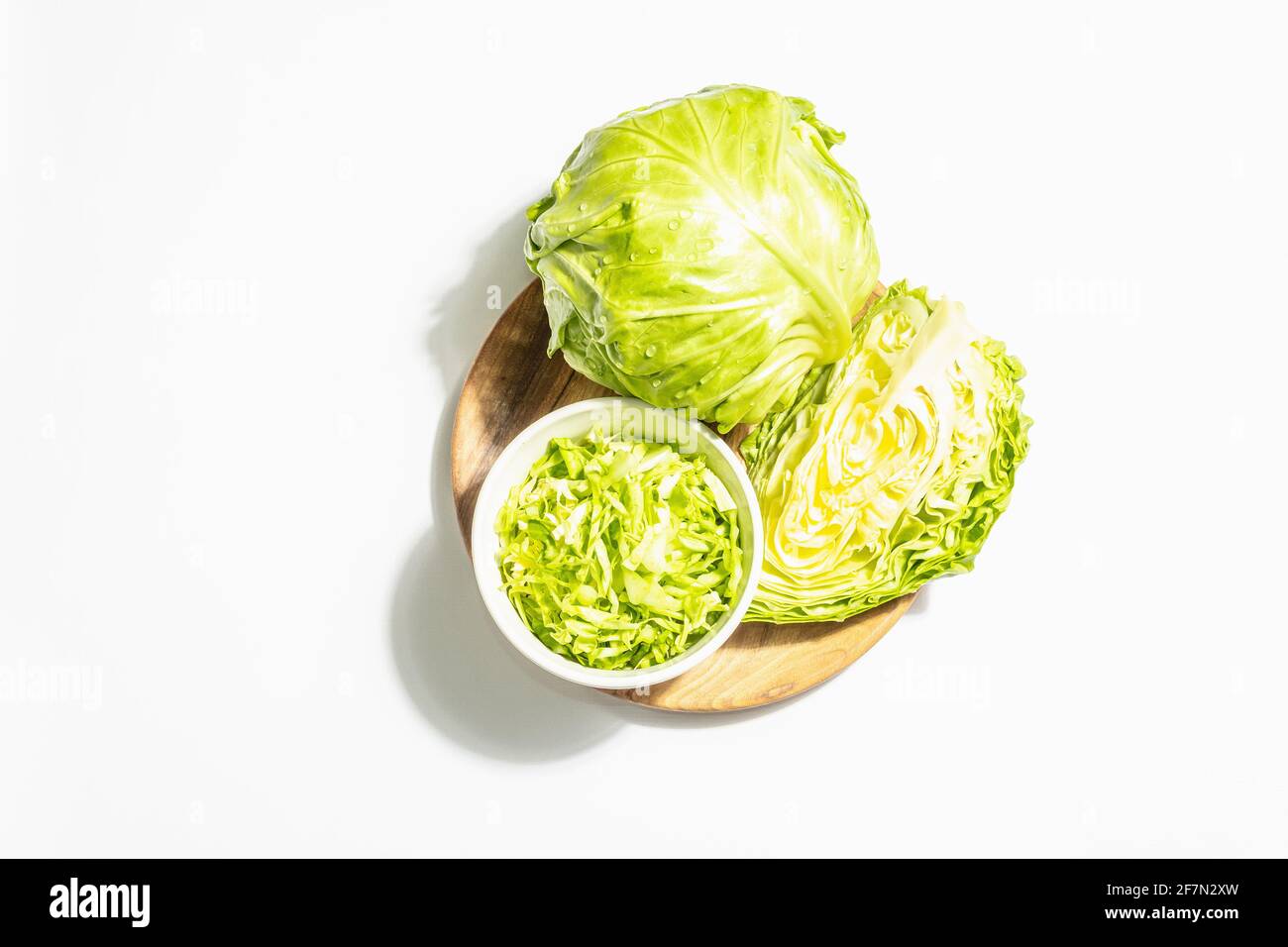 Fresh young shredded cabbage, whole head and cut piece isolated in