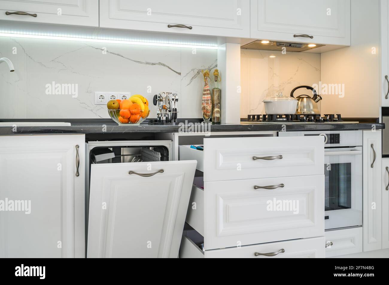 Luxurious white modern kitchen interior, drawers pulled out, dishwasher