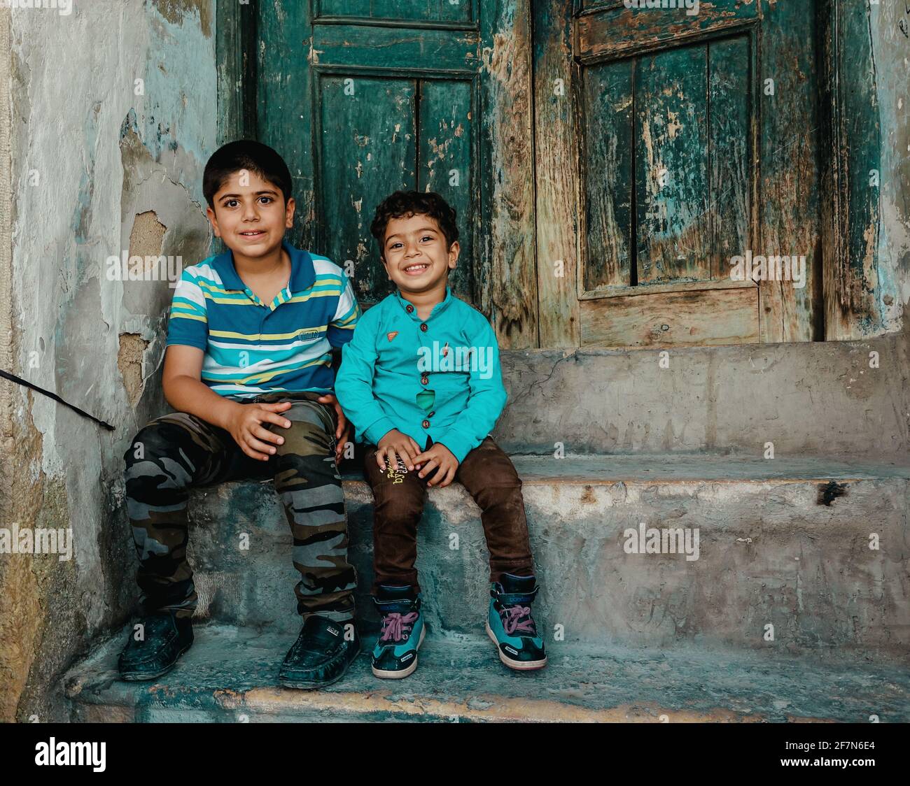 baghdad, Iraq - april 8, 2017:  two kids sitting on the old wood door Stock Photo