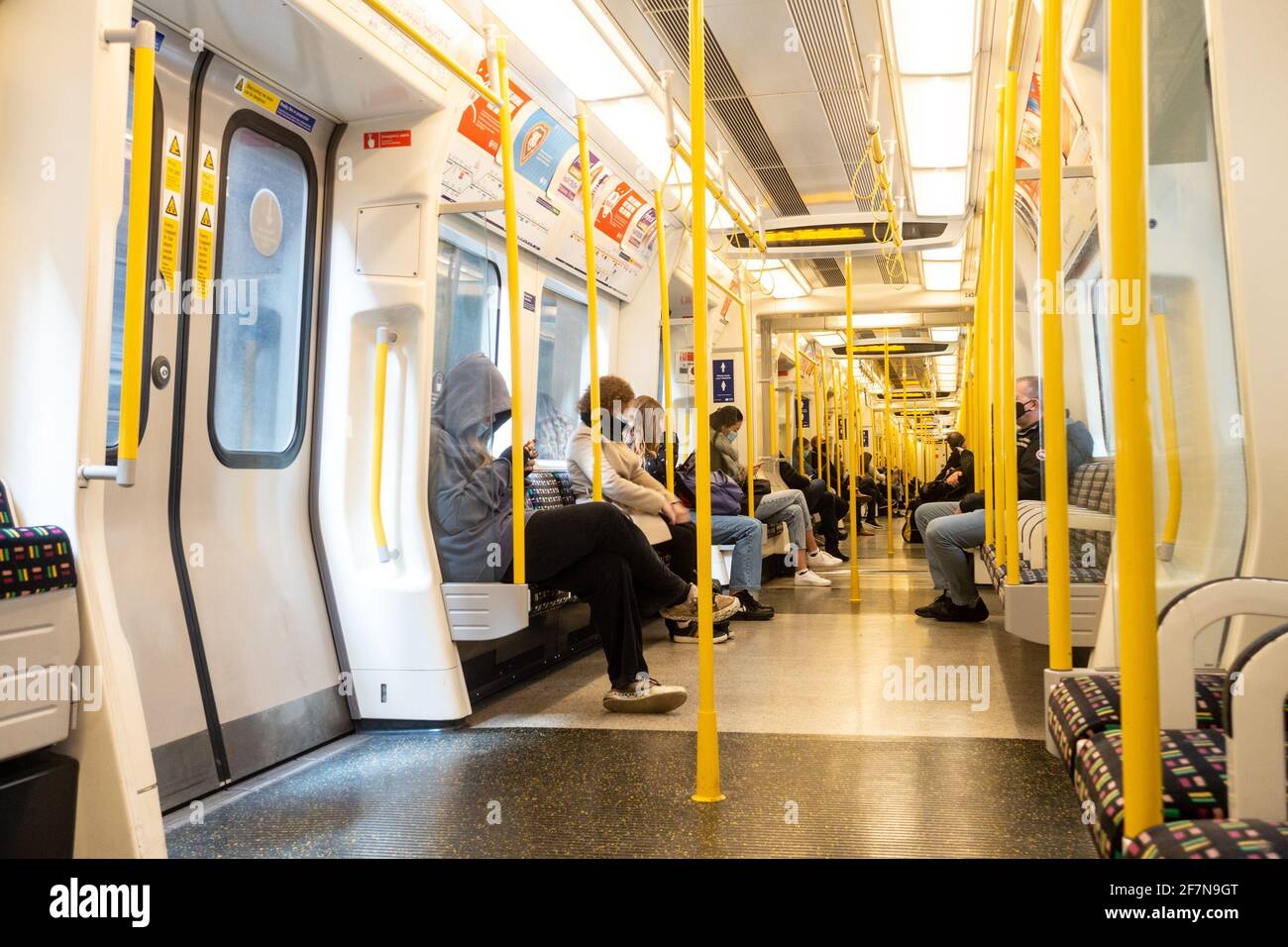 Onboard a London Underground train on the District Line. The train is relatively empty due to coronavirus and all passengers are seated. Stock Photo