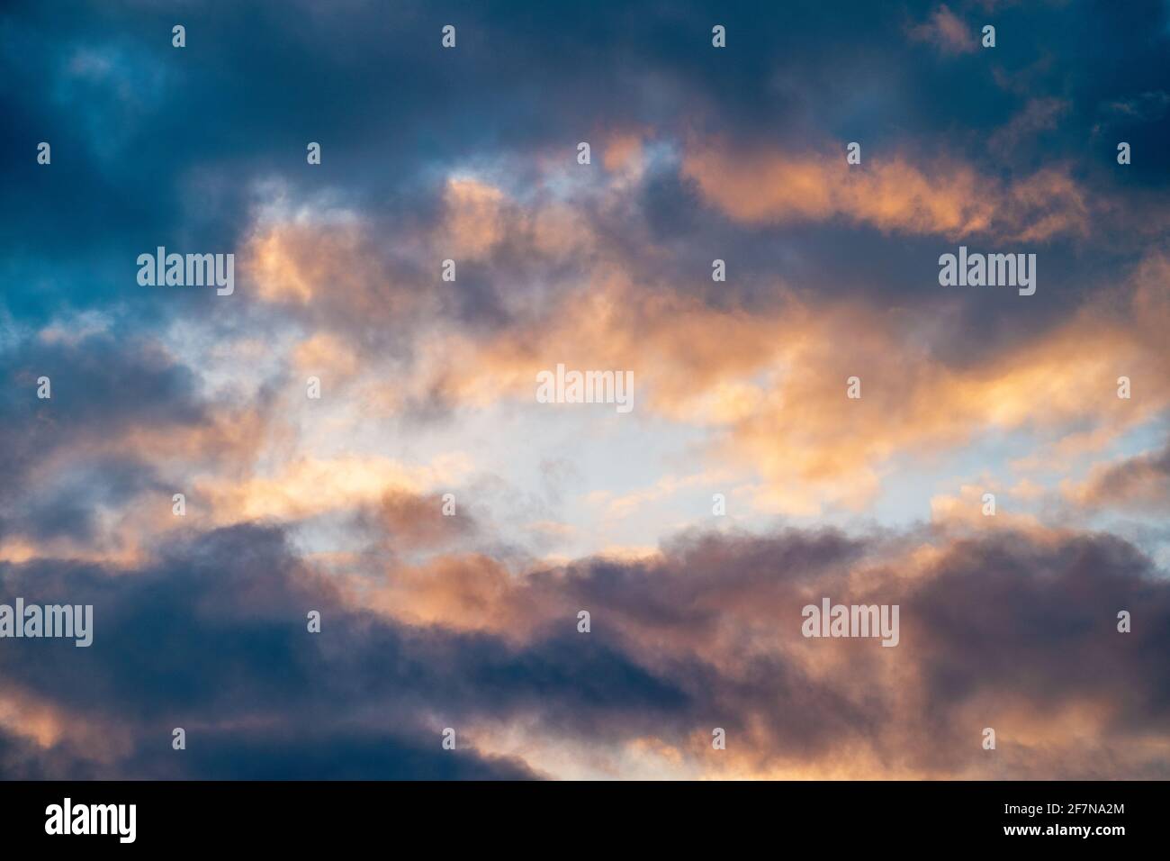 Colorful cloudy sky background, sunset cloudscape with blue overcast as frame and and light yellow-orange heaven in center, abstract nature background copy space. Stock Photo