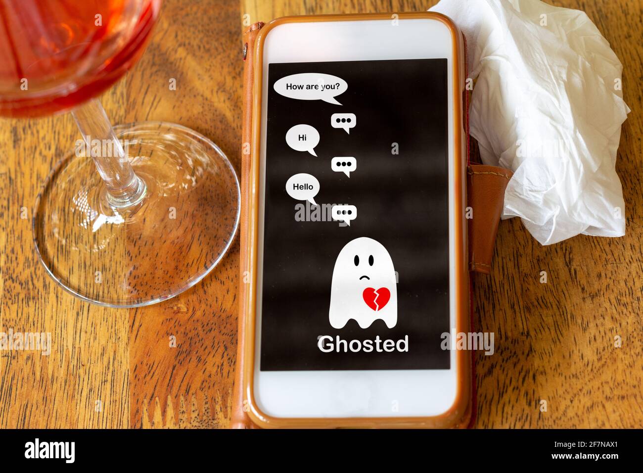 Ghosted on mobile phone on table with glass of wine and tissue, Ghosting to cut all communication without explanation, ending a relationship. Social m Stock Photo