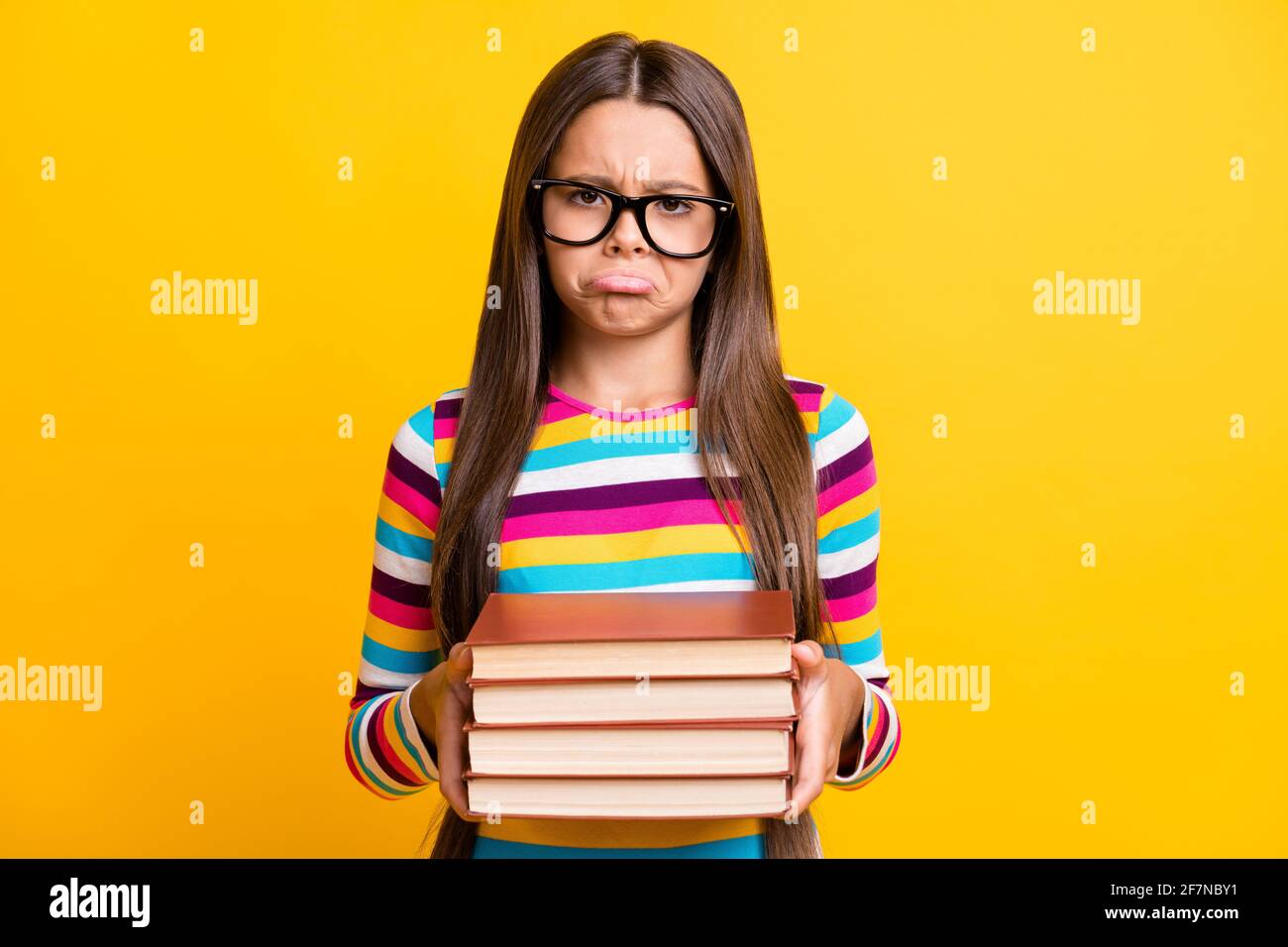 Photo portrait of sad upset little girl keeping books don't want to do  homework wearing glasses isolated on bright yellow color background Stock  Photo - Alamy