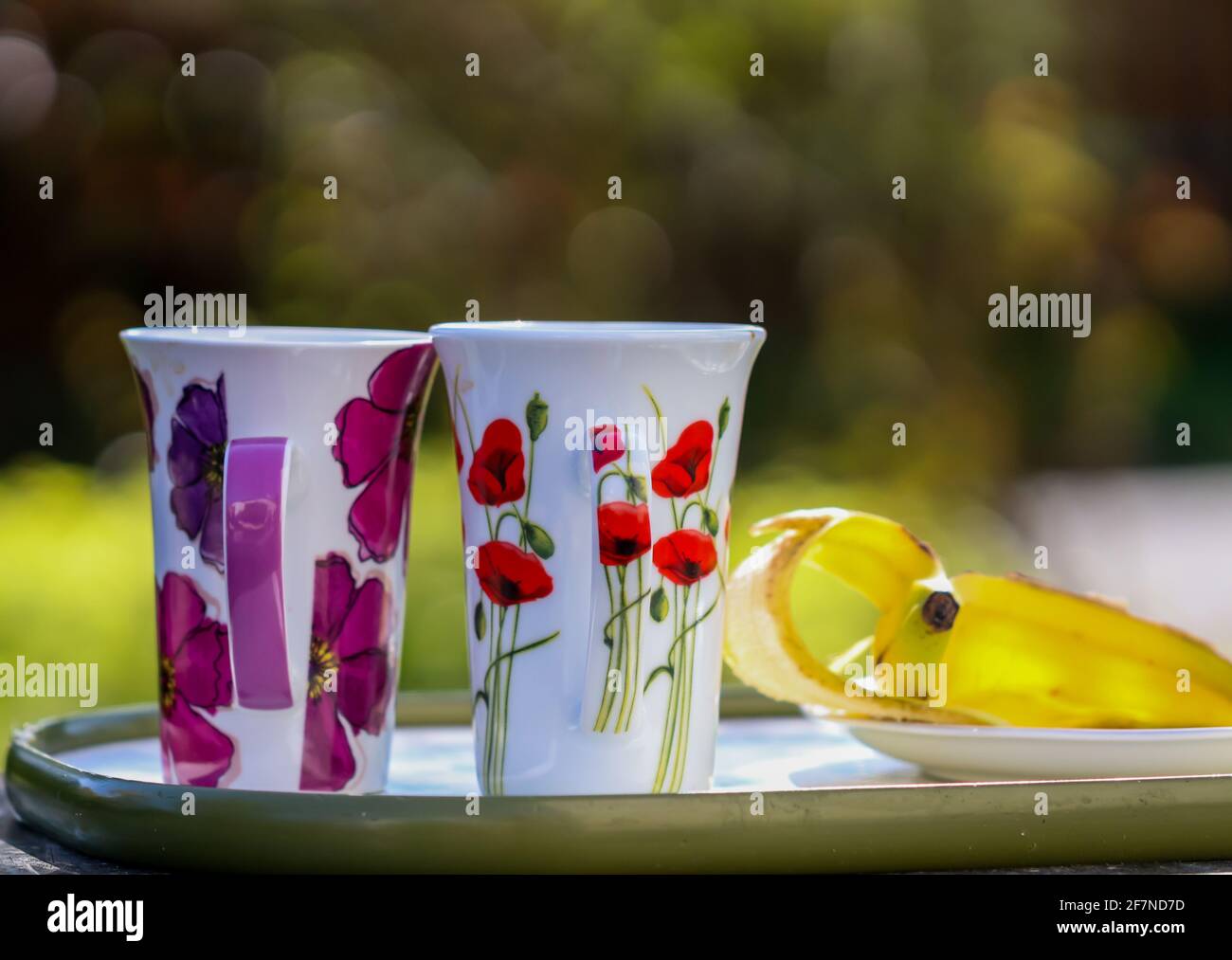 Two cups and a banana skin on a picnic table after entertaining a guest in the garden Stock Photo