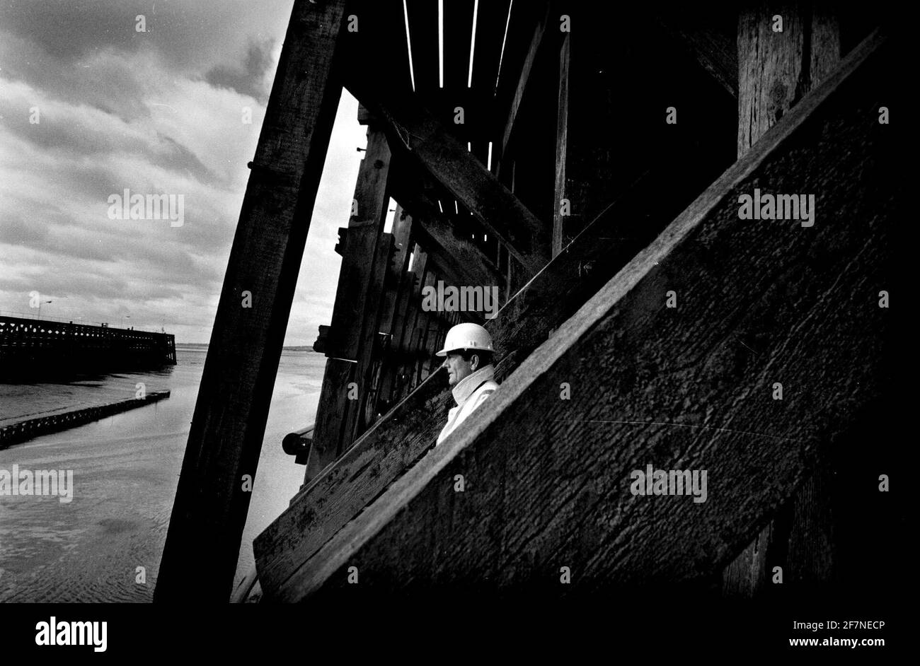 PHIL WHITE SITE SUPERVISOR INSPECTS THE OLD AND NEW TIMBERS OF SHARPNESS NORTH PIER WHICH DATES BACK TO 1870S AND IS UNDERGOING EXTENSIVE REPAIRS. BRITISH WATERWAYS WHO ARE UNDERTAKING THE WORK ARE USING HUGE GREENHEART TIMBERS  TO REPAIR THE PIER. Stock Photo