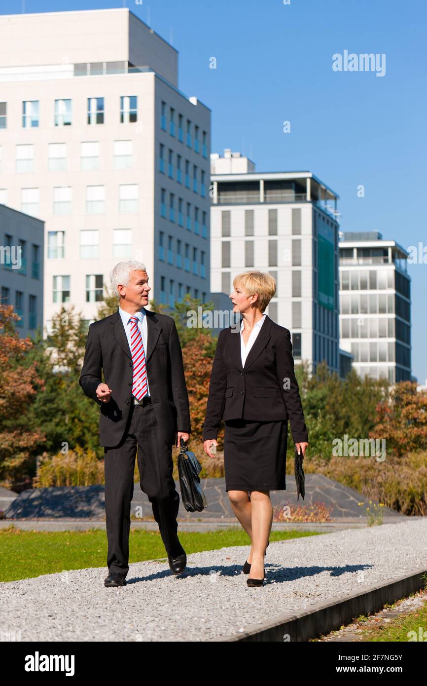 Business people talking outdoors and walking in a park Stock Photo