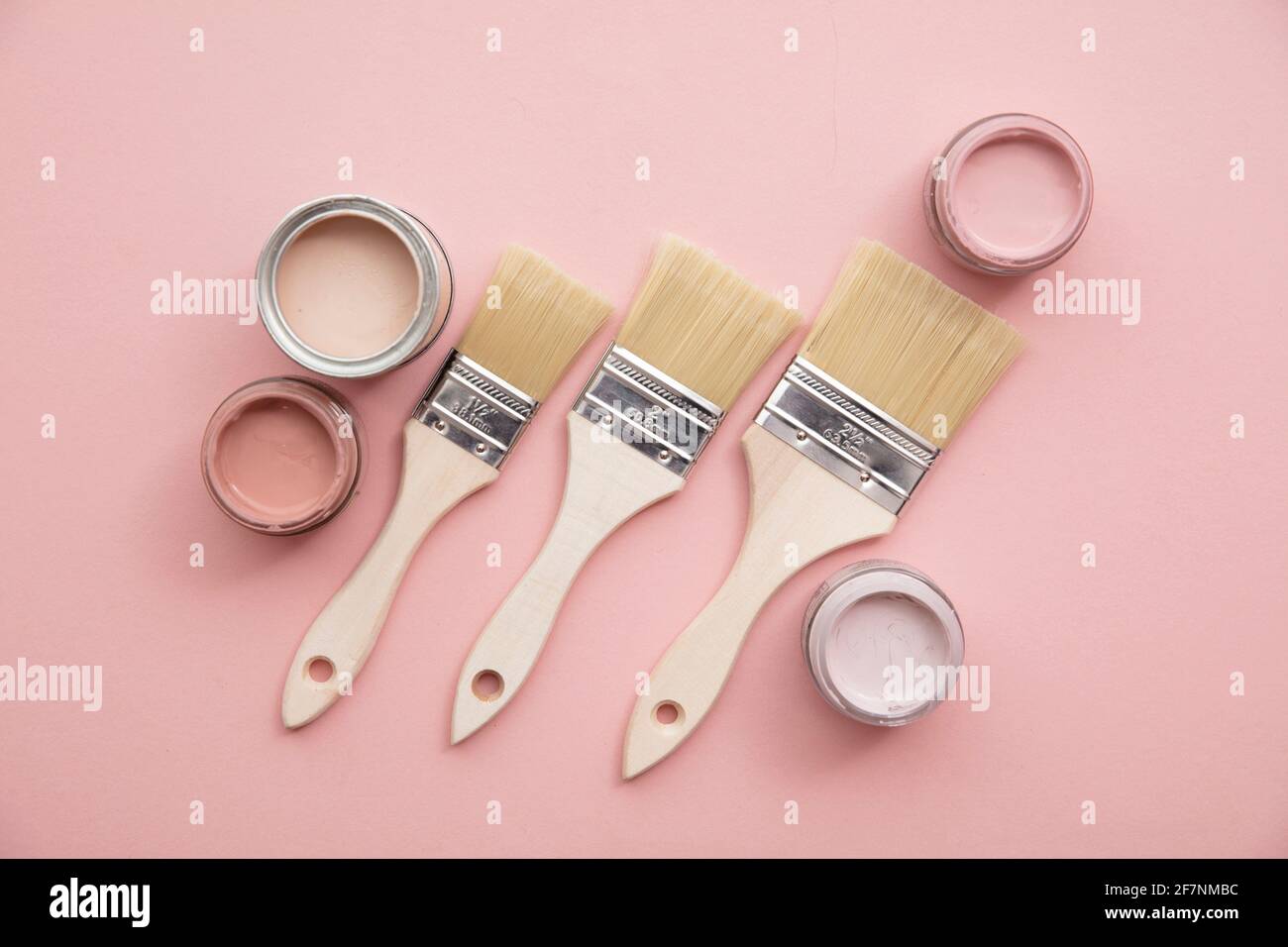 Overhead view of a DIY paint brush with pastel pink sample paint pots