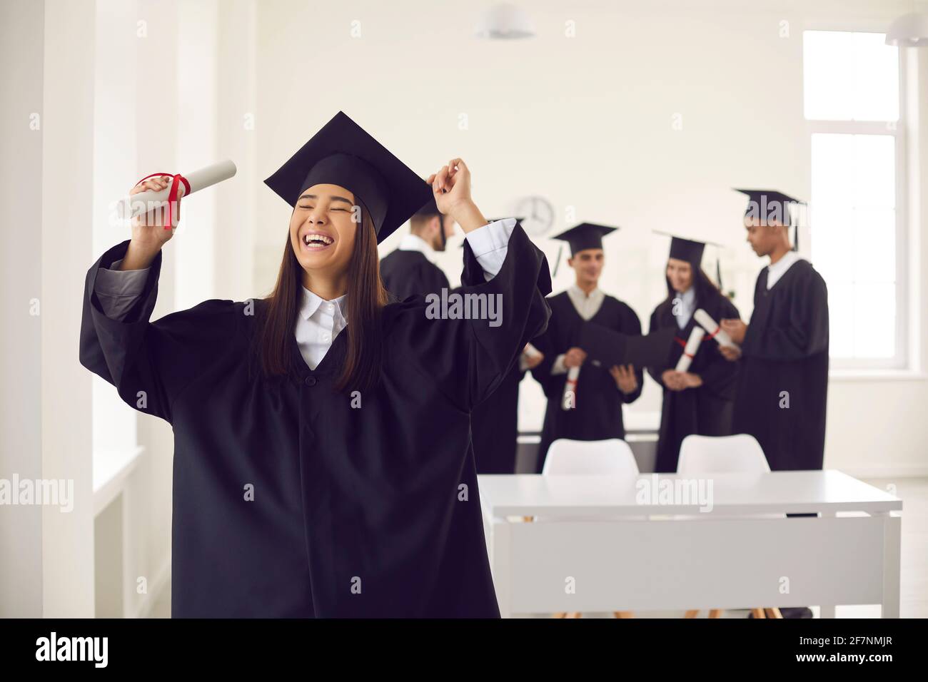 Laughing asian girl student university graduate celebrating getting diploma Stock Photo