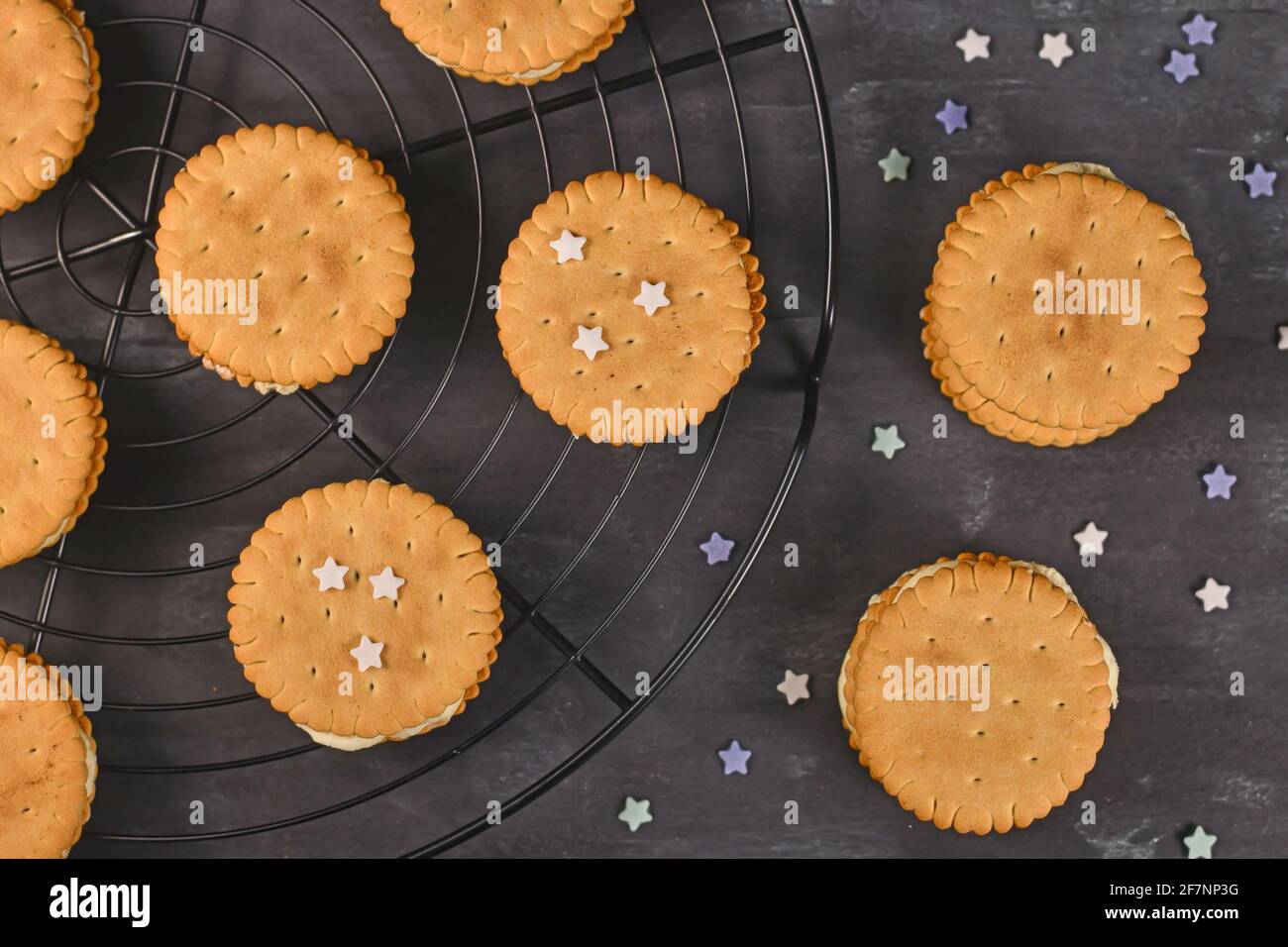 Cream filled sandwich cookies with sprinkles on dark background Stock