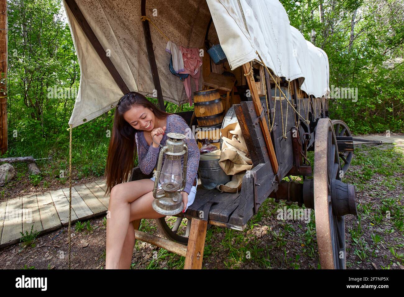 Filipino female traveler sitting on aged wagon and examining retro oil