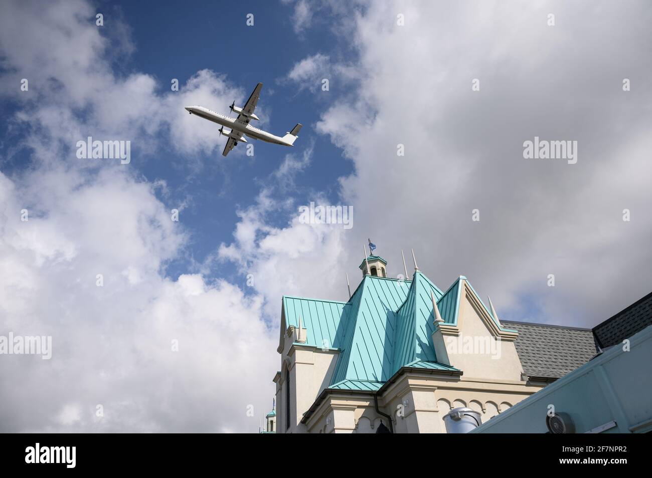 Domestic propeller airplane flying in the blue sky over roof of ...