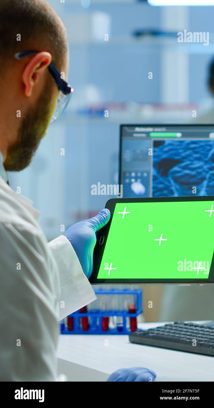Researcher holding and looking at tablet with chroma key display in ...