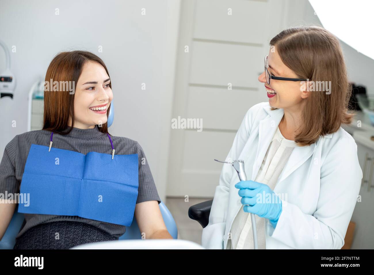 Dentist doctor treats a patient in a clinic. Young woman with white and healthy teeth. Stock Photo