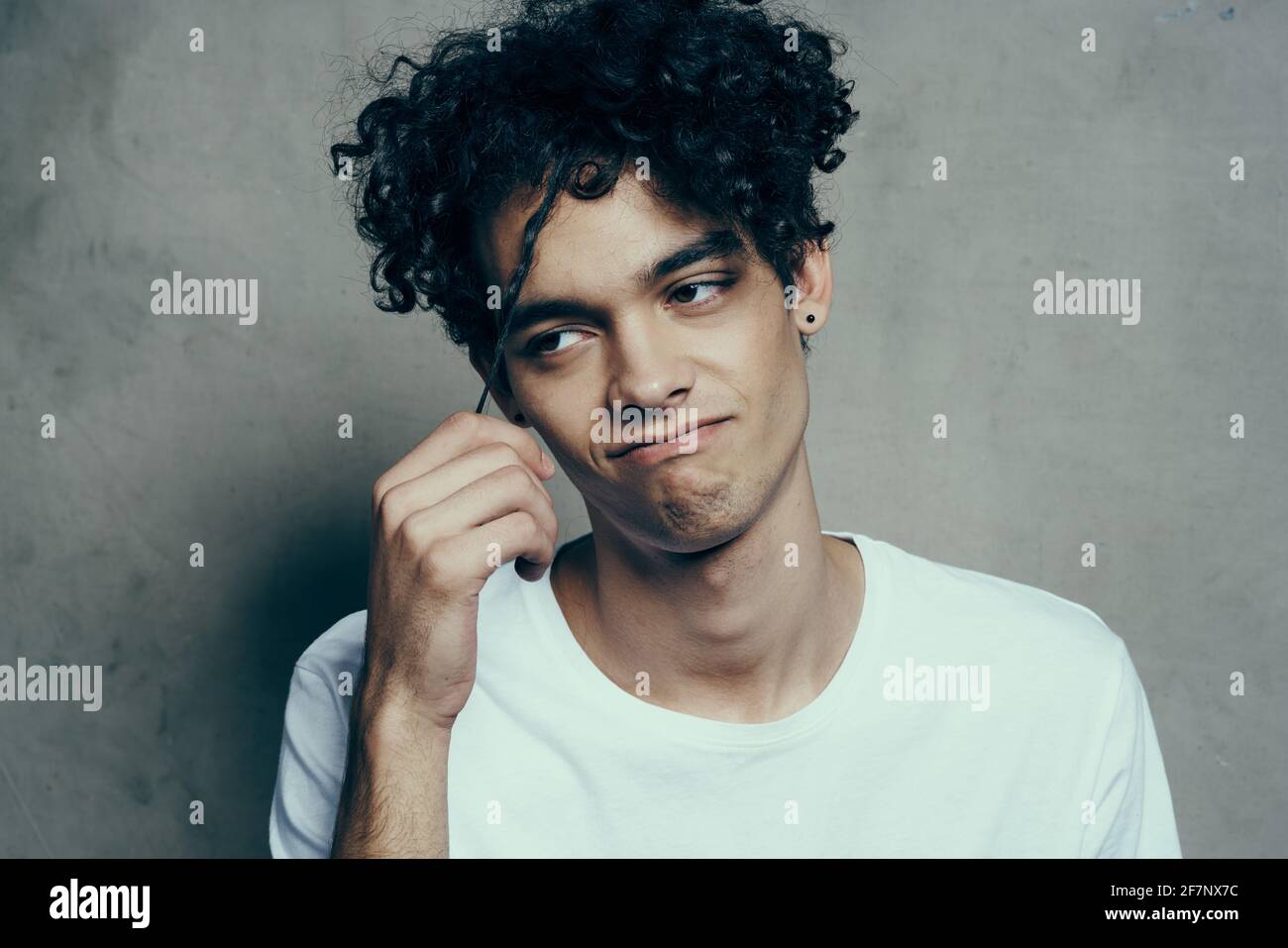 Cheerful guy with curly hair white t-shirt gray background model cropped  view Stock Photo - Alamy