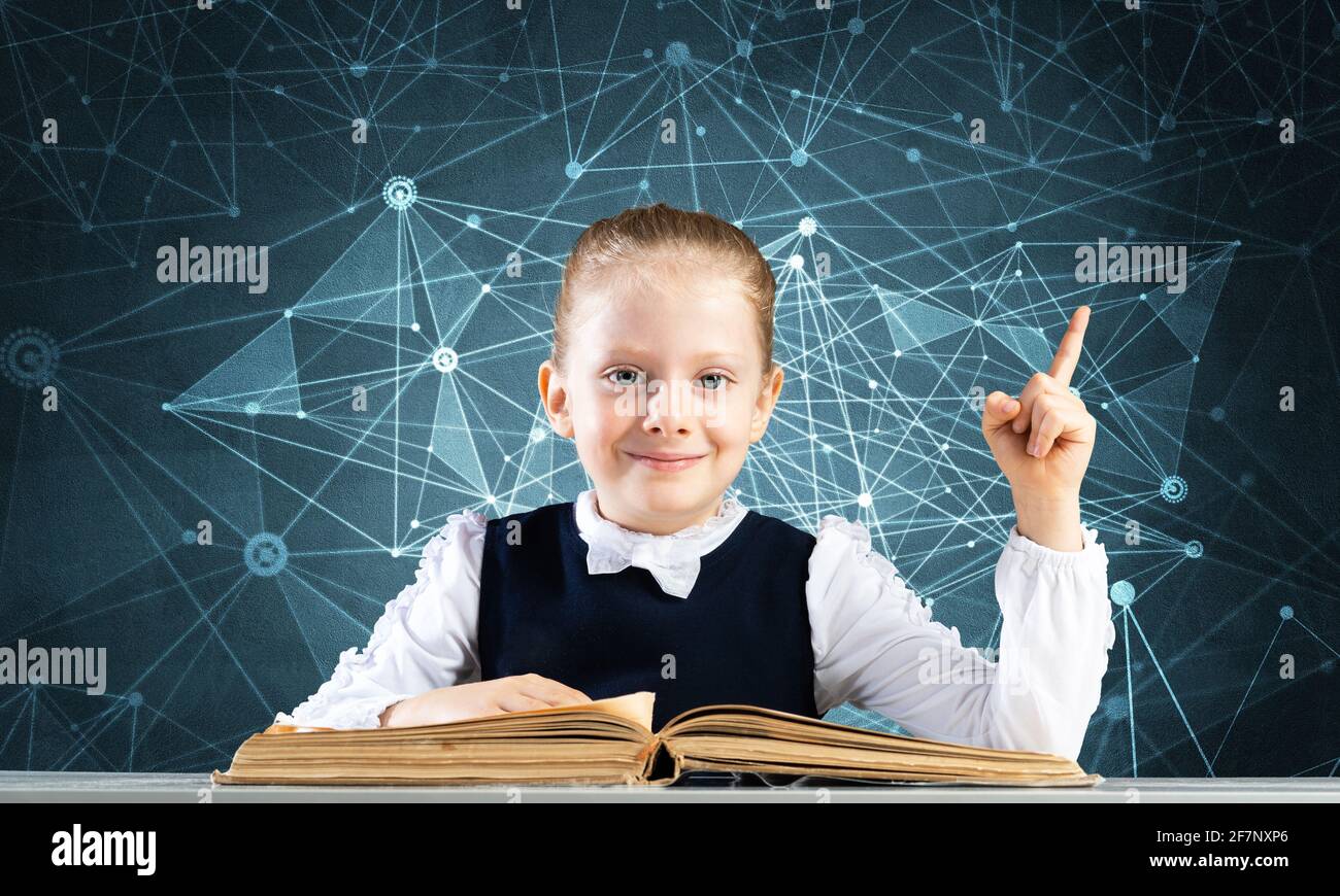 Smiling little girl sitting at desk with open book Stock Photo - Alamy