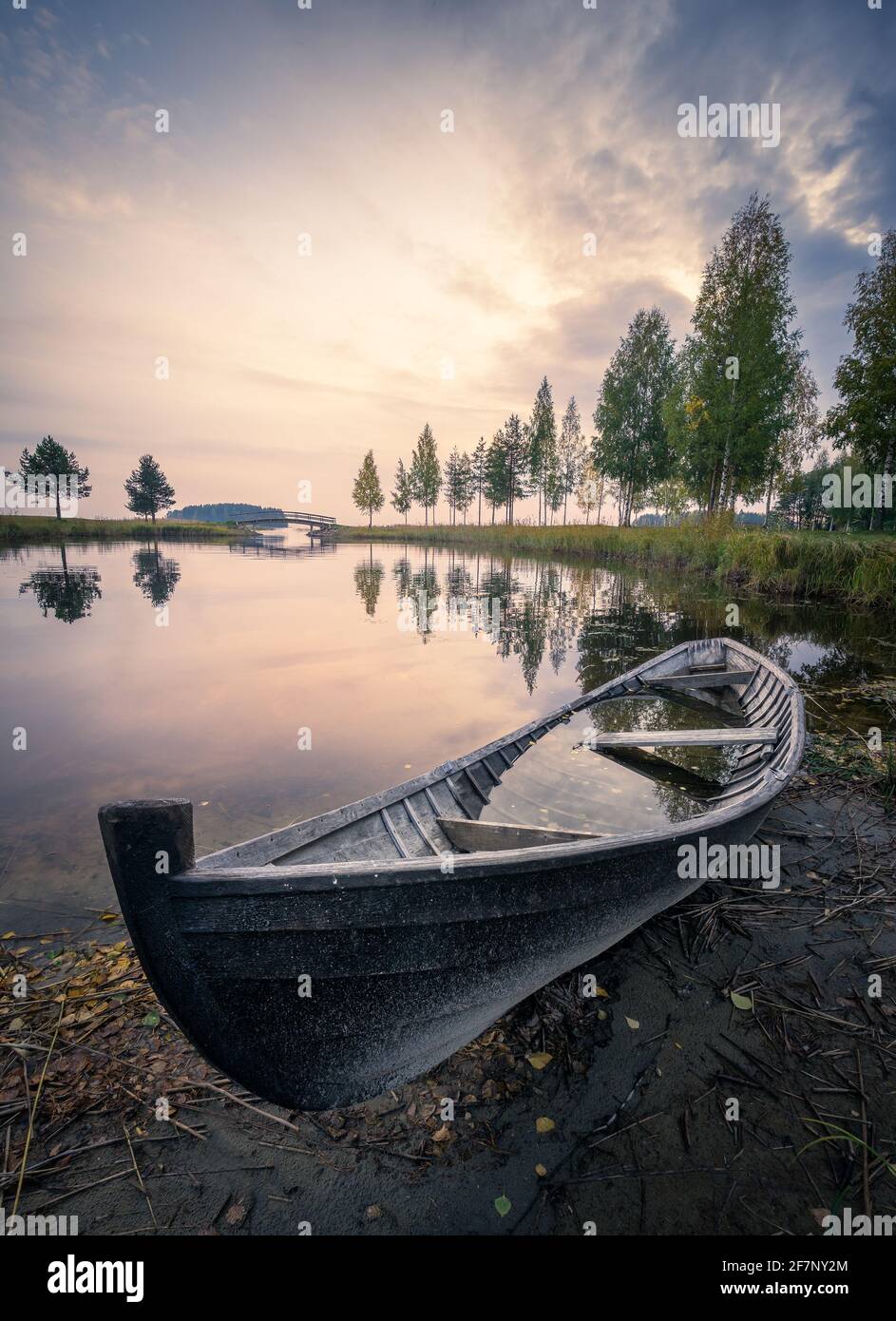 Old rowboat with calm lake and mood sunset at autumn evening in Finland Stock Photo