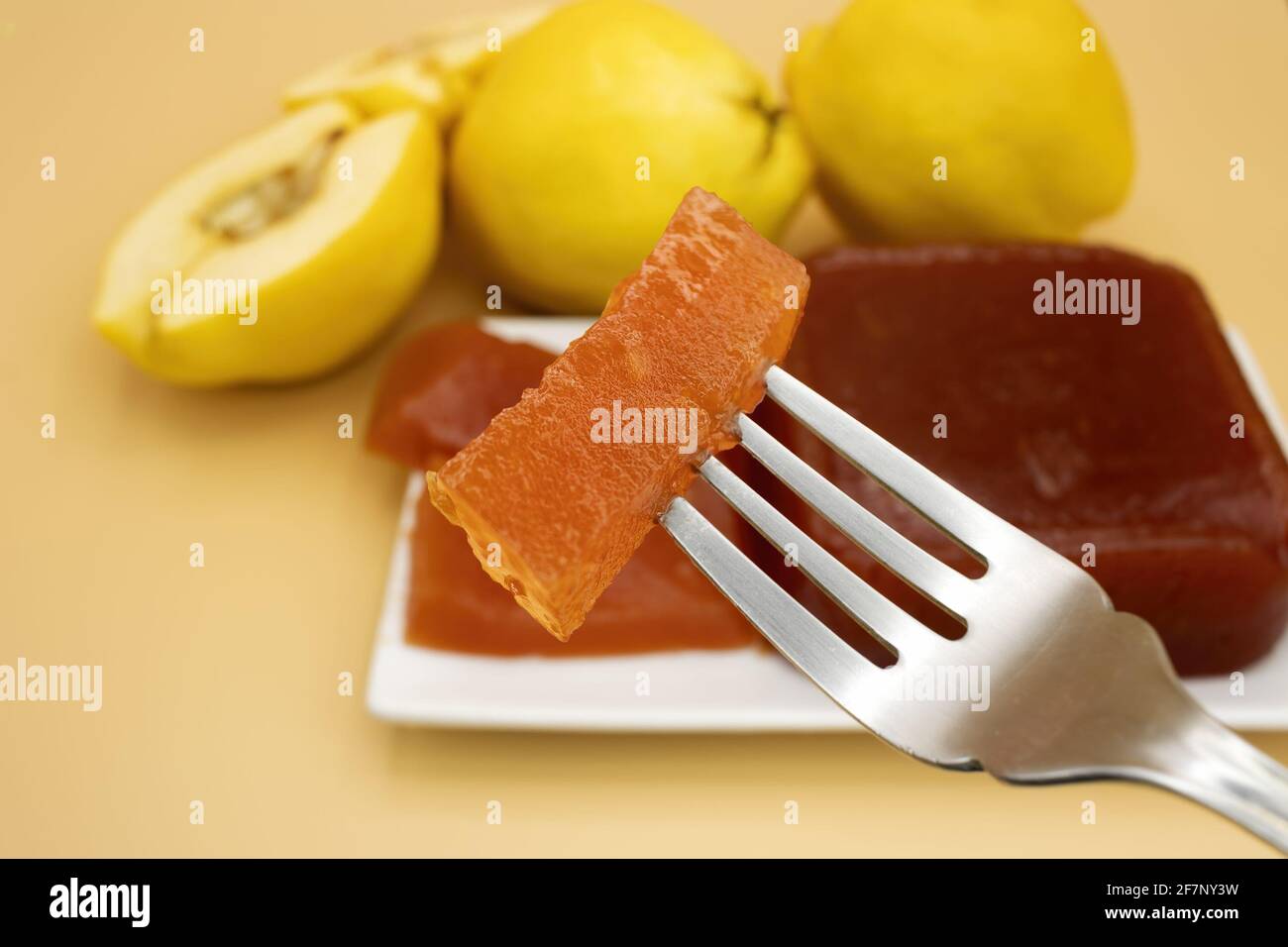 Selective focus on a delicious homemade quince jam, homemade quince flesh, on a creamy background, with quinces out of focus in the background Stock Photo