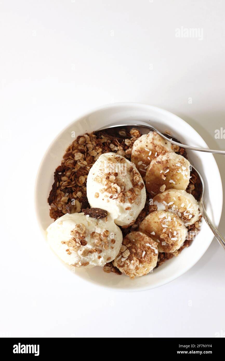 Fresh Granola Served with Ice-Cream Scoops and Banana Slices.  Home Dessert Bowl. Stock Photo