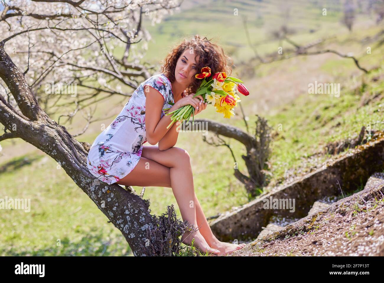 A beautiful woman with a bouquet of flowers poses in nature during the ...