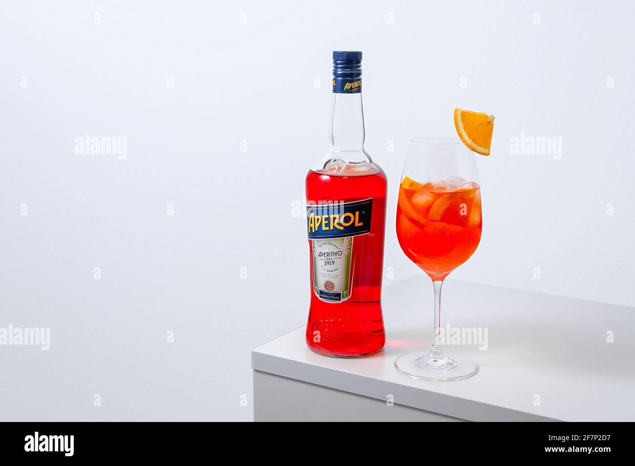 Lugansk, Ukraine - March 29, 2021: Aperol Spritz Cocktail. Aperol in bottle and wine glass with ice on white background. Long fizzy drink. Minimal cre Stock Photo