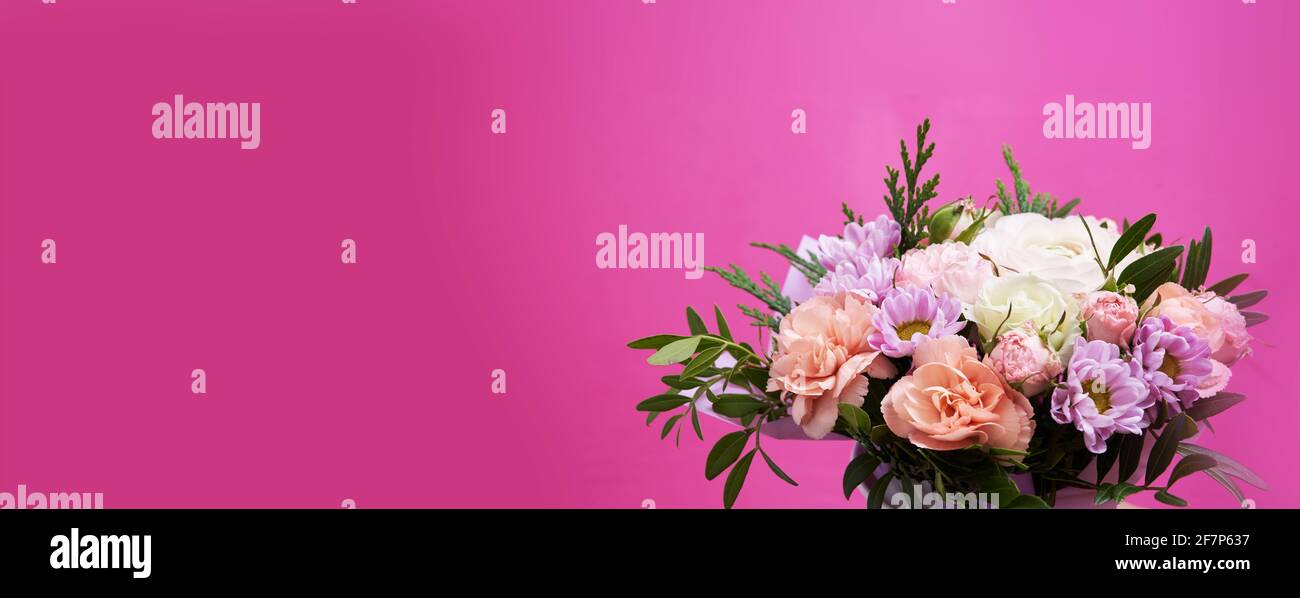 Beautiful bouquet of mixed different flowers in hand on pink background banner with copy space, greeting, gift Stock Photo