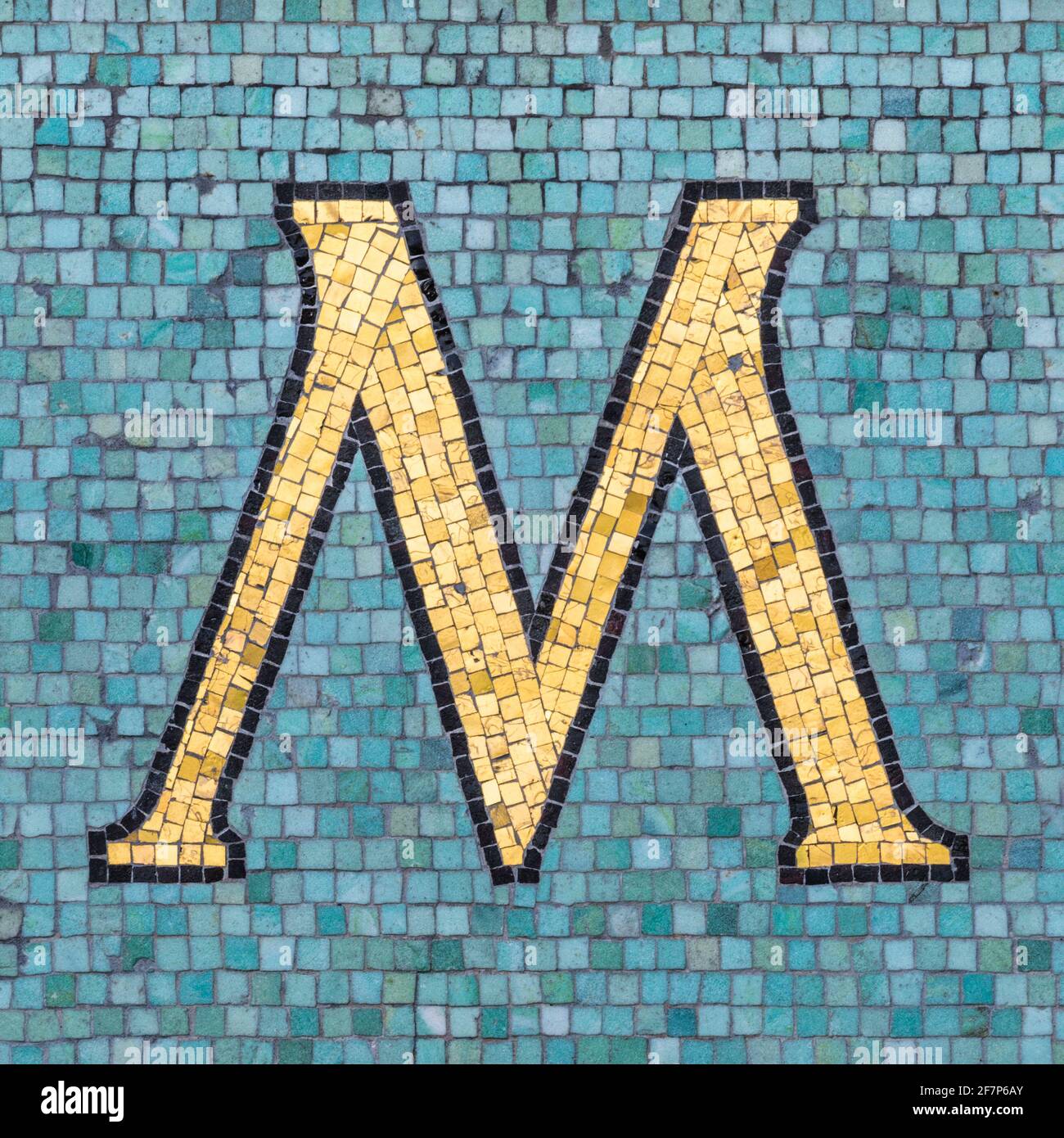 Golden mosaic letter M with black outline in turquoise blue mosaic