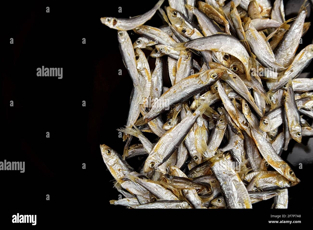 Dried salted small fish on black background, top view, copy space. Stock Photo