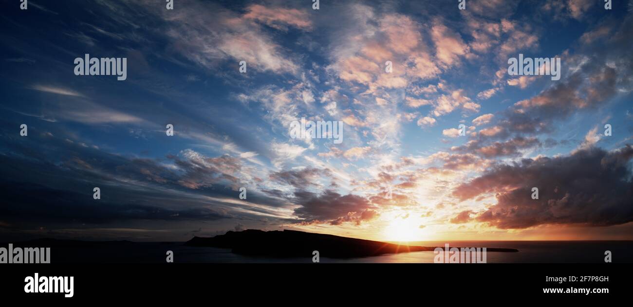 The sun sets over the sea horizon. Sunset on the sea against the backdrop of the island Stock Photo