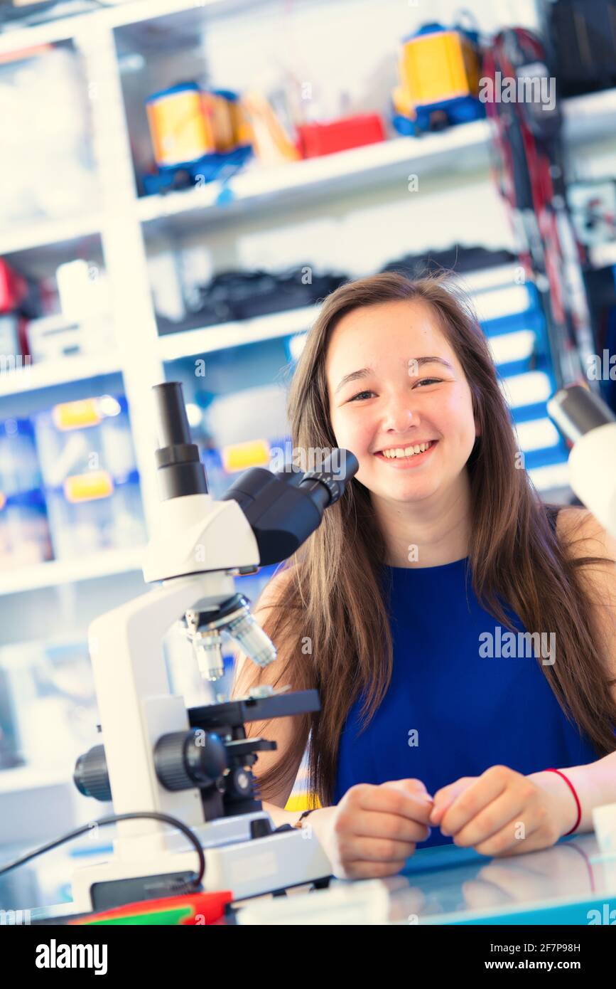 Schoolgirl girl with a microscope in the laboratory. Binocular microscope in a school laboratory Stock Photo