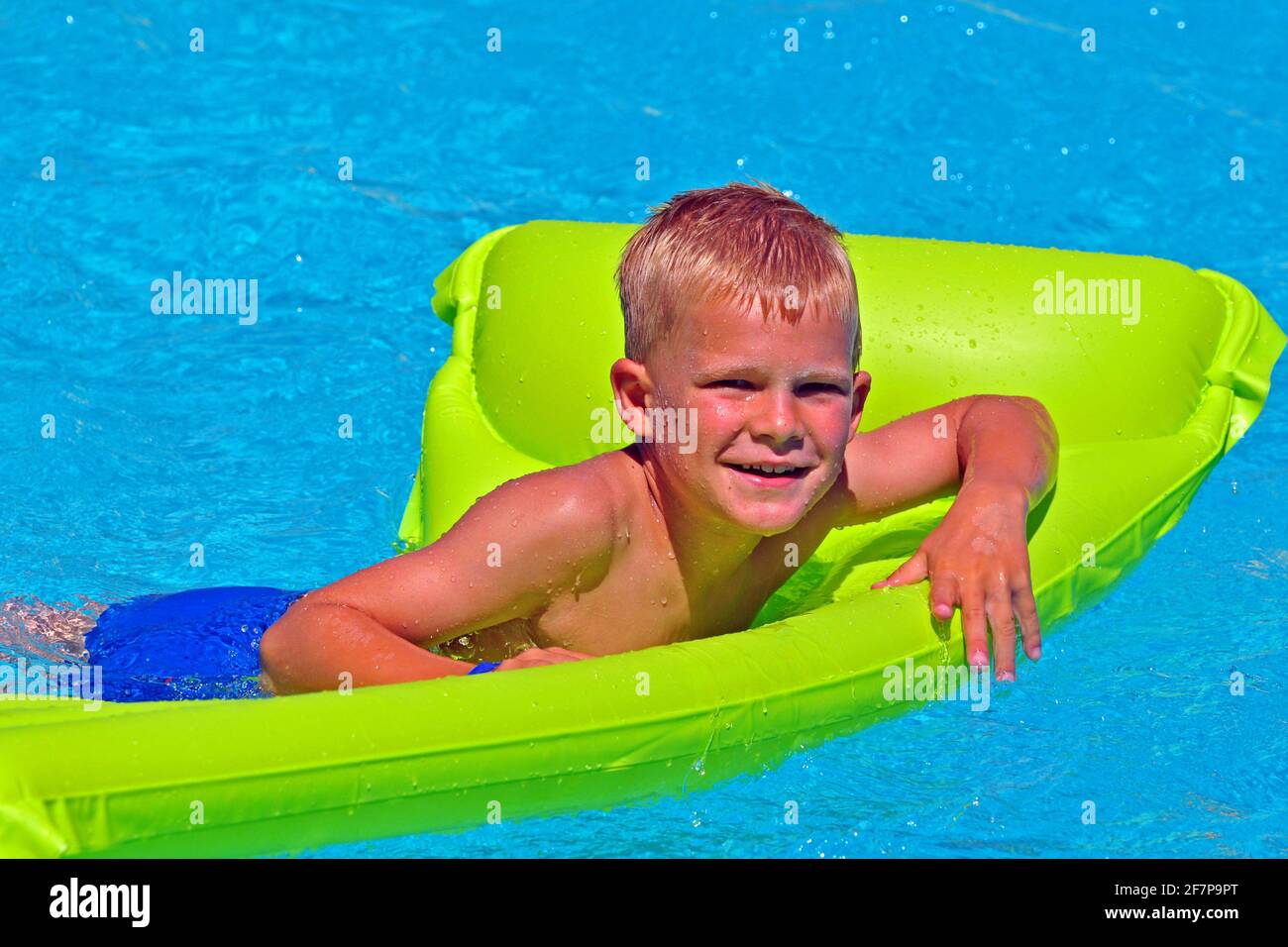 seven years old boy bathing in the swimming pool with an air mattress