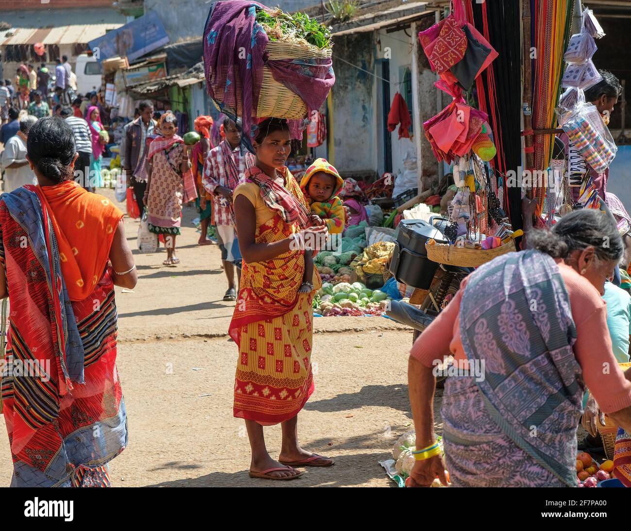 Koraput, India - February 2021: Adivasi woman from the Kondh tribe with her child shopping vegetables in the Koraput market on February 21, 2021 in Od Stock Photo