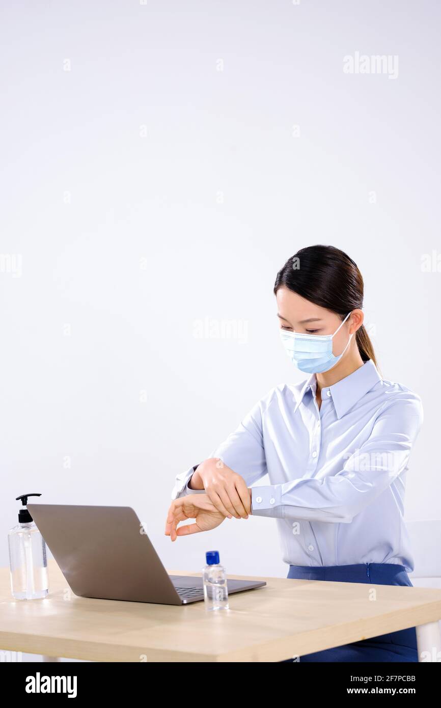 A business woman wearing a mask uses hand sanitizer side view Stock Photo