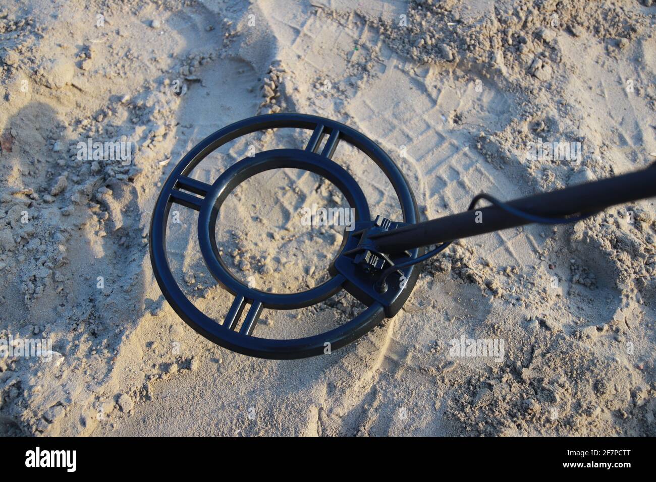 Metal detector coil looking for a treasure on sand Stock Photo