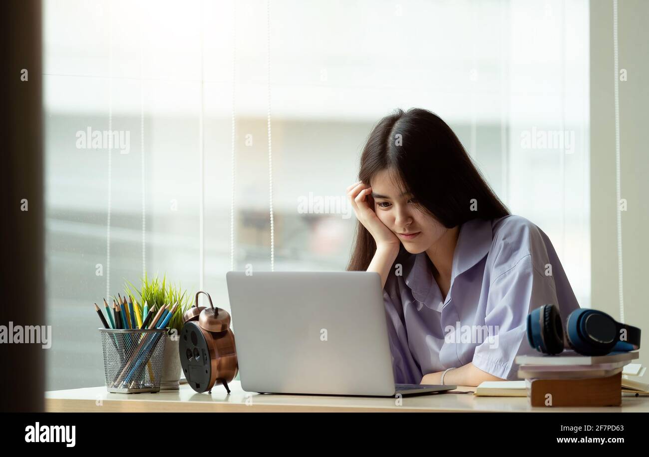Online education. Asian girl with headphones makes an online lesson using a computer video call to a virtual teacher at home Stock Photo