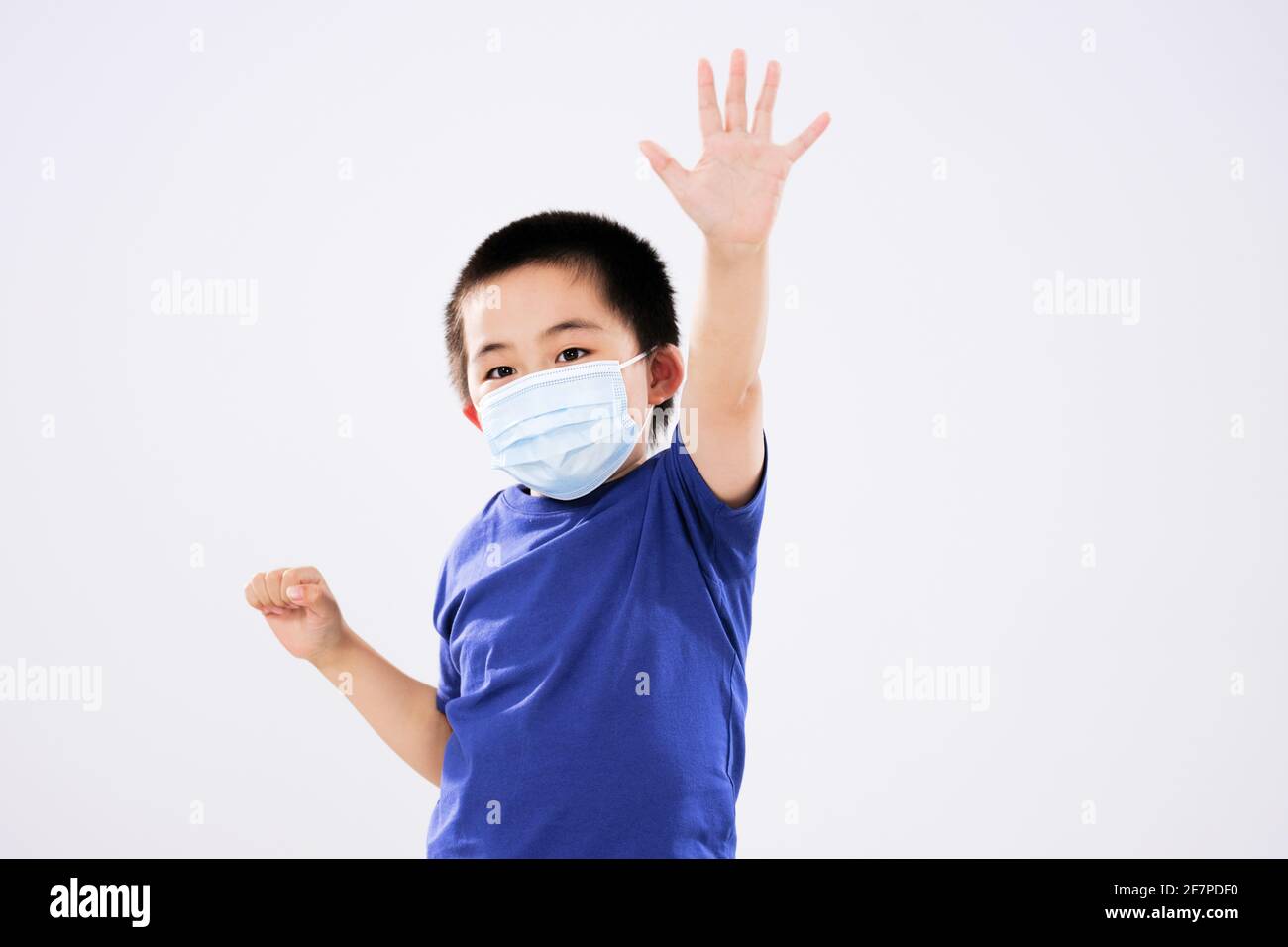 A little boy with a mask raised his arm not looking at the camera Stock Photo