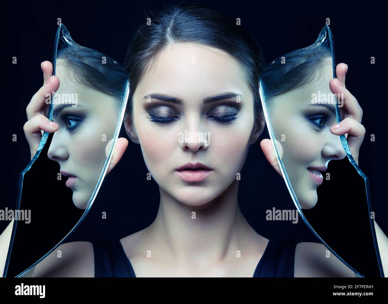 Girl with a shard of the mirror. Female with mirror shard in hand posing on gray background