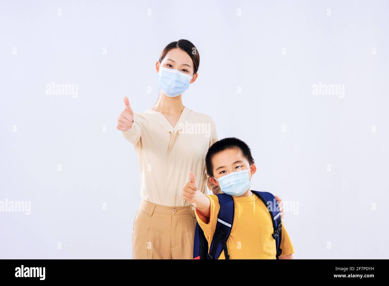 Mom and the little boy with the mask put up their thumbs smiling Stock Photo