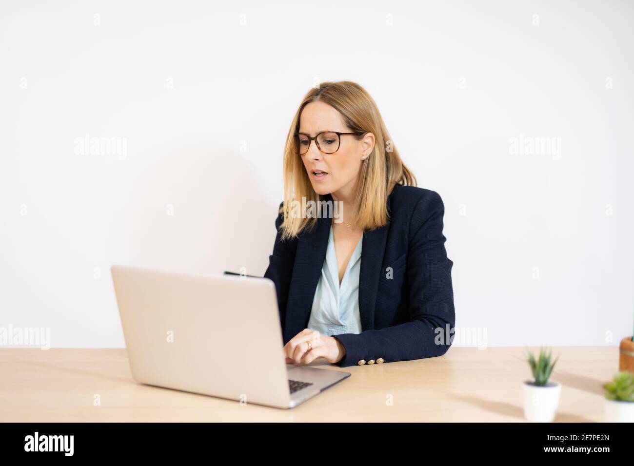 Concentrated young beautiful business woman working on laptop in office ...