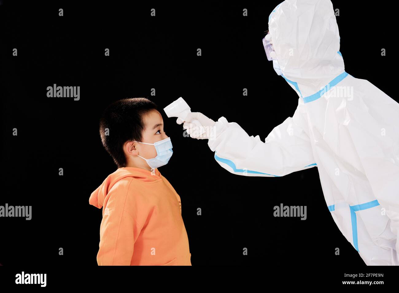 The woman doctor in medical protective clothing took the boy's temperature face to face Stock Photo