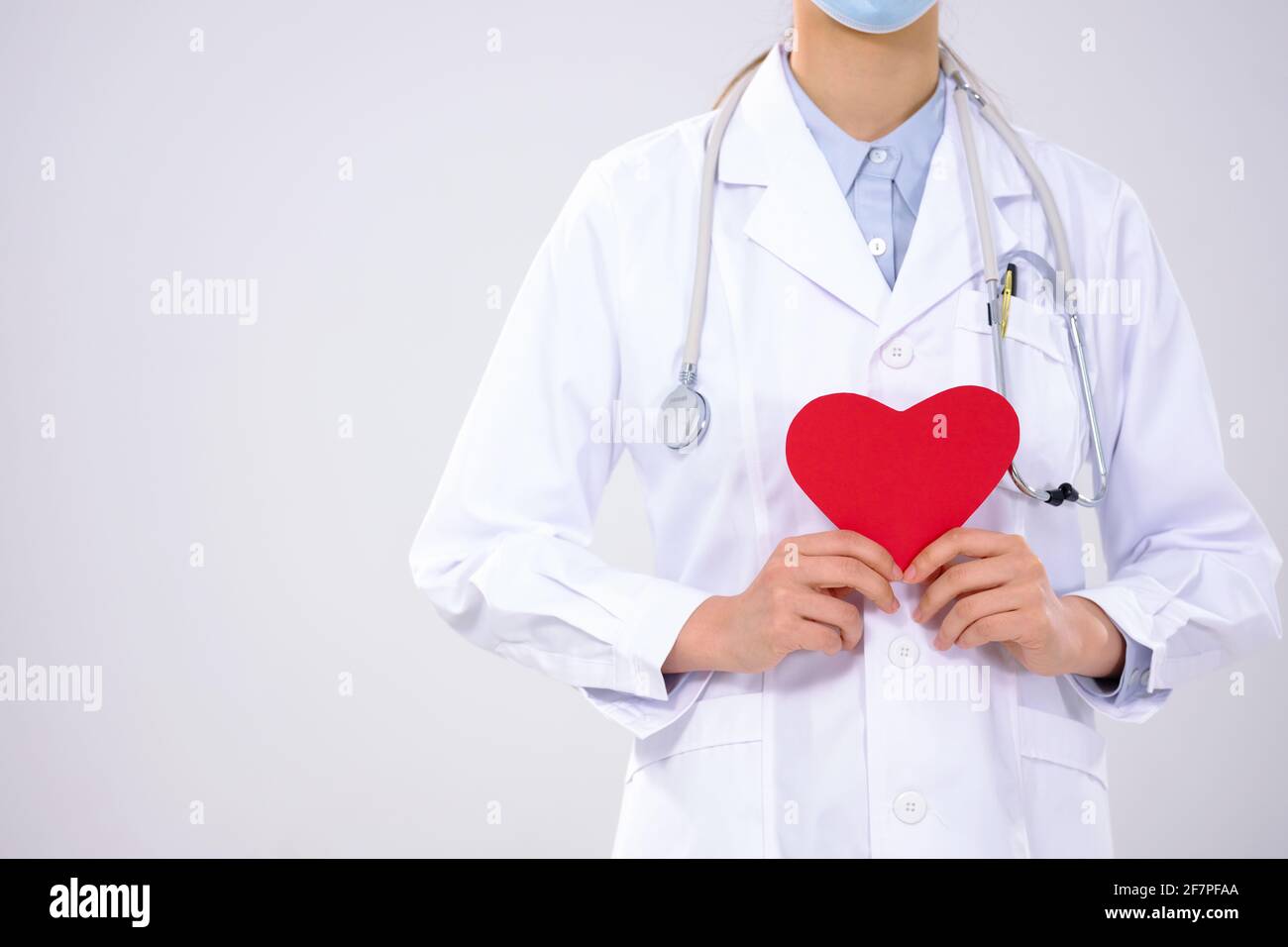 A young woman doctor with a mask has a red heart close-up Stock Photo