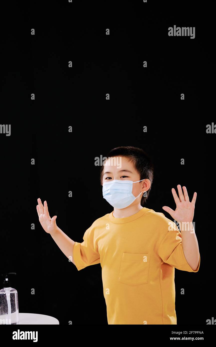 The little boy with mask shows his hands after using hand sanitizer with joy Stock Photo