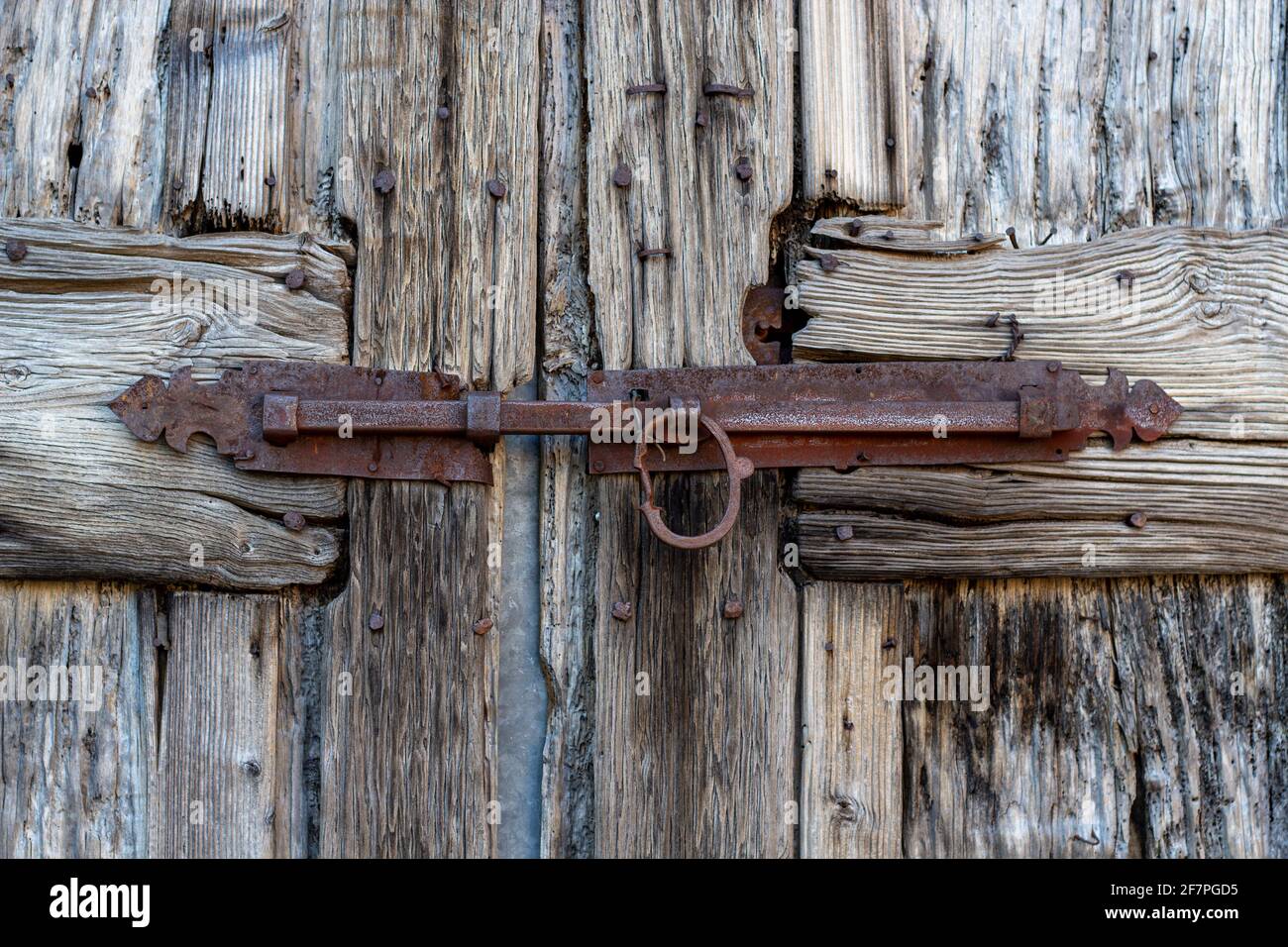 Detail of a rusted iron bolt lock on the old wooden door. Close up Stock Photo