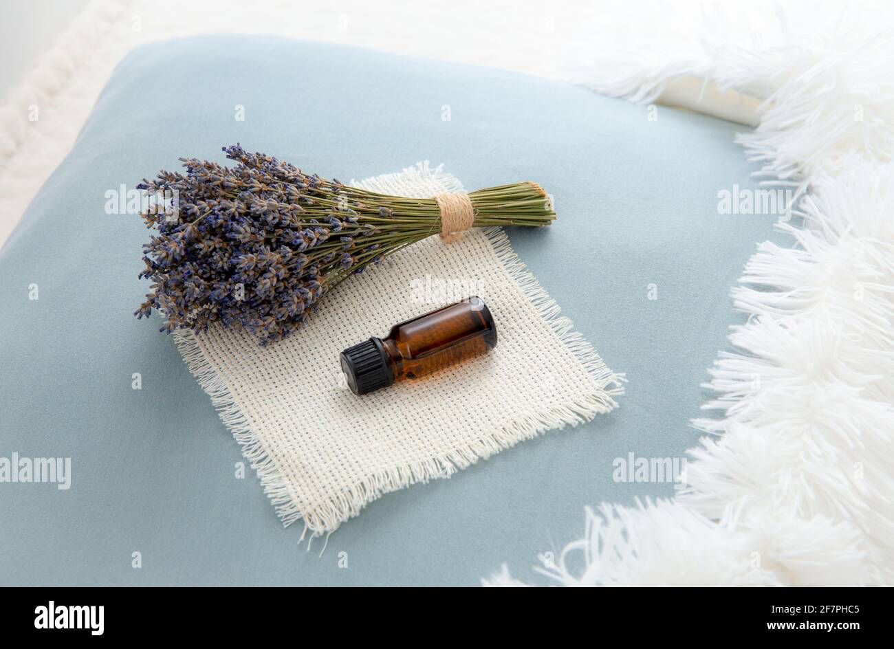Using lavender flower essential oil for better good night sleep. Aromatherapy concept. Lavender oil and bouquet of dried lavender flowers on pillow. Stock Photo
