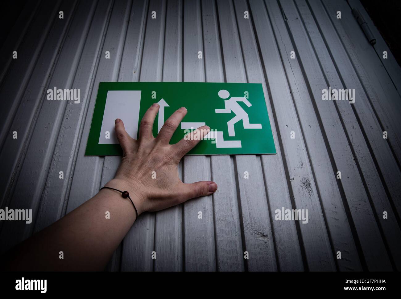 Person try escape from indoors. Hand push exit sign door. Crime horror concept. Stock Photo