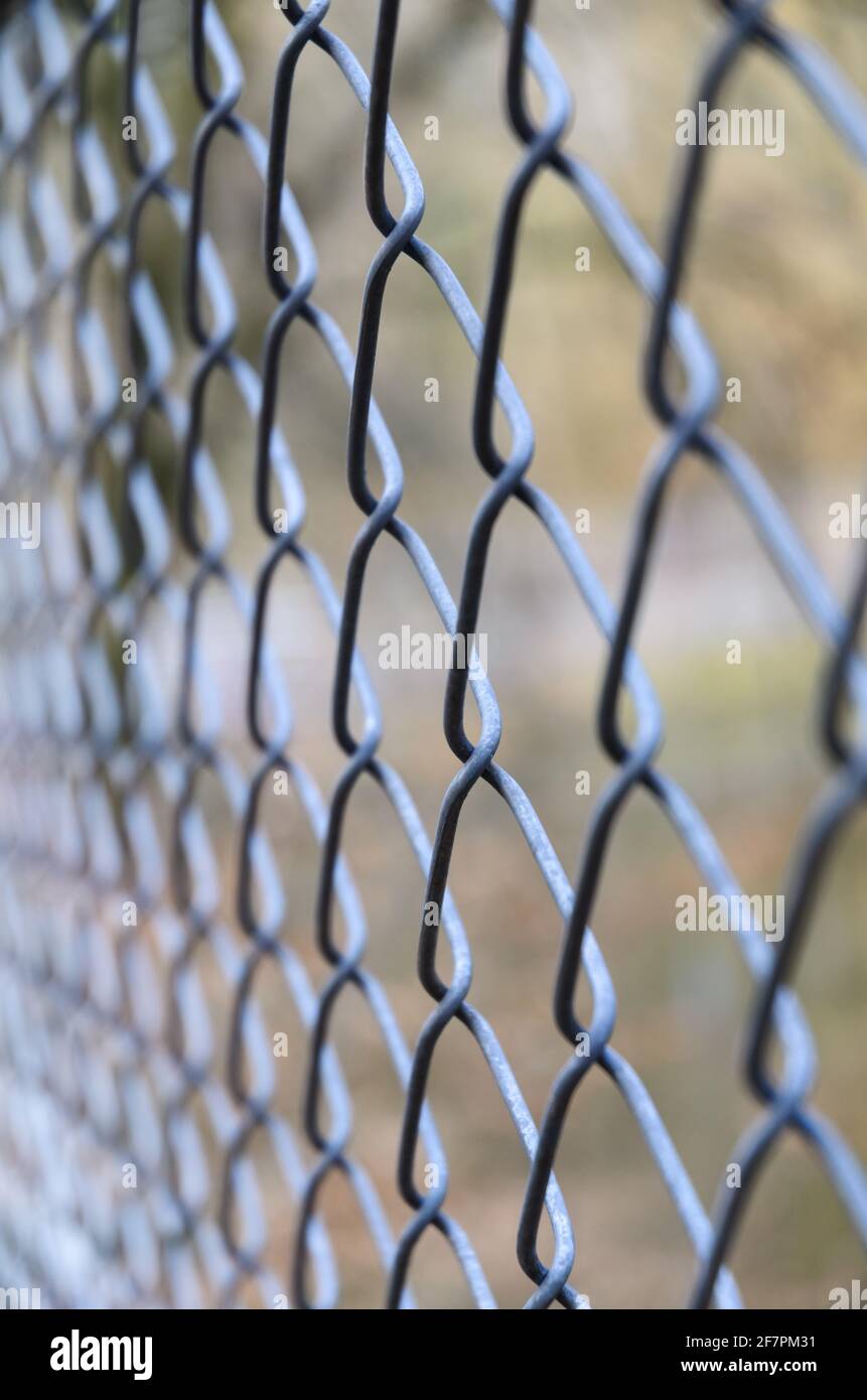 Close-up of metal chain-link fence, diamond pattern, with shallow depth of field or selective focus, abstract background or backdrop Stock Photo