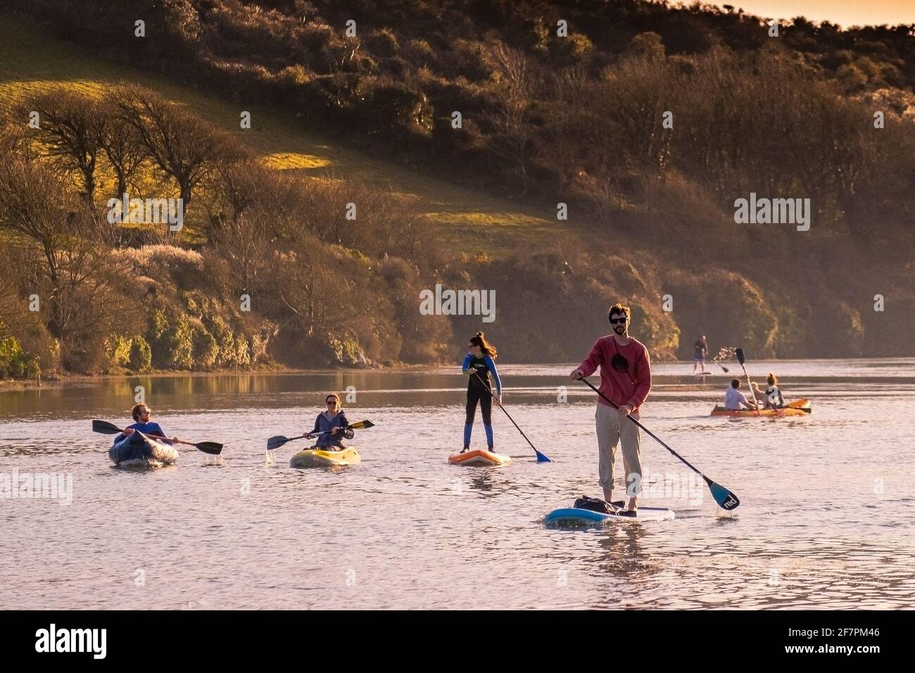 People paddling on the Gannel River in kayaks and on paddleboards in
