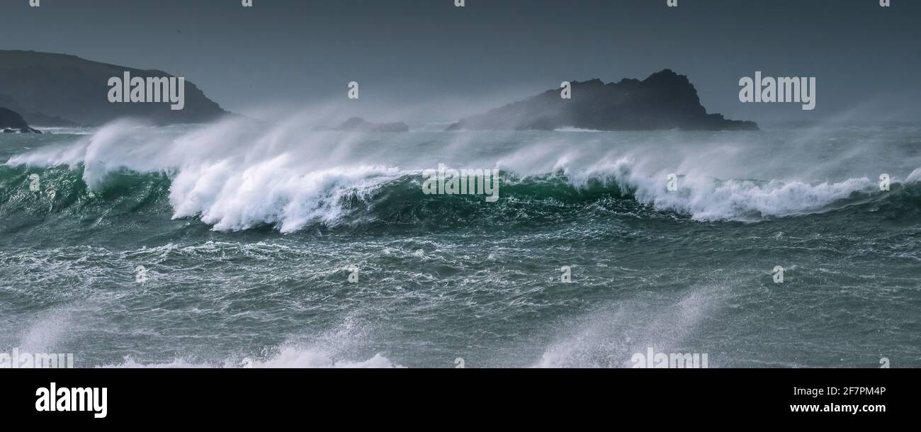 A panoramic image of wild waves breaking and choppy sea around The Goose Island off the Pentire Point East headland in Fistral Bay in Newquay in Cornw Stock Photo