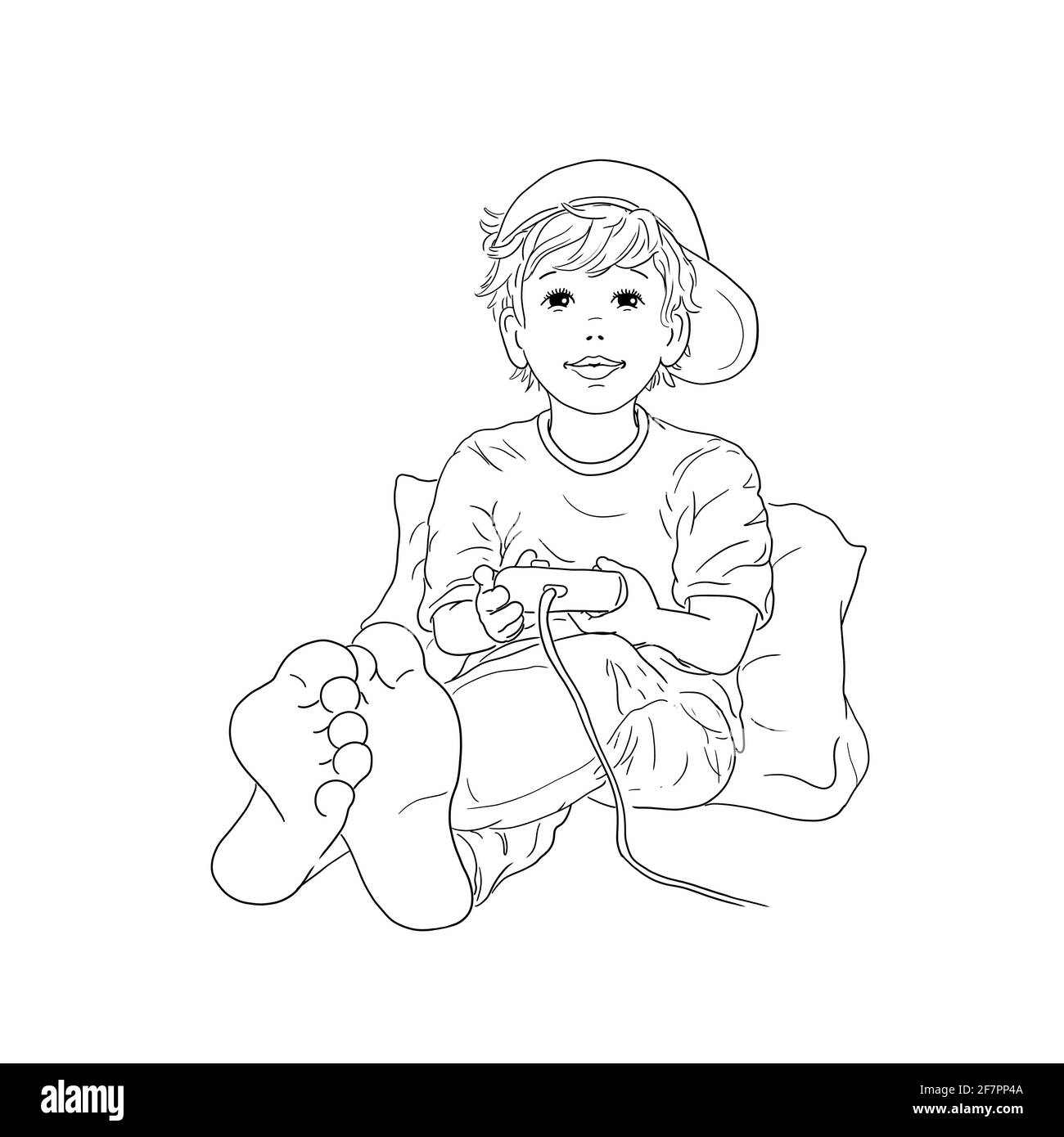 Boy sitting barefoot leaning against pillow with hat baseball cap on his head and playing computer game console play leisure hobby teenager pupil chil Stock Photo