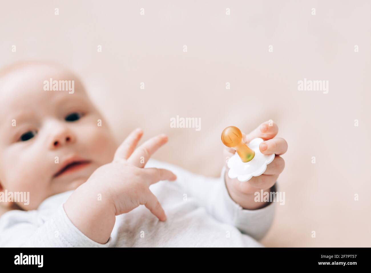 Newborn baby lying on the bed and holding pacifier in his hands. Caring for newborn children